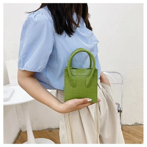 Green faux-crocodile texture mini handbag worn by a model with a gold chain strap