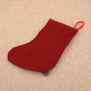 Detail of red textured burlap Christmas stocking with wooden tag on linen background