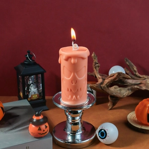Macro detail of orange pumpkin face pillar candle on silver metal holder for Halloween