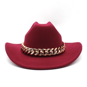 Detail of deep red wool cowboy hat featuring a bold polished gold metal chain band