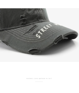 Detailopname van grijze distressed honkbalpet met Street Wear borduursel en scheuren