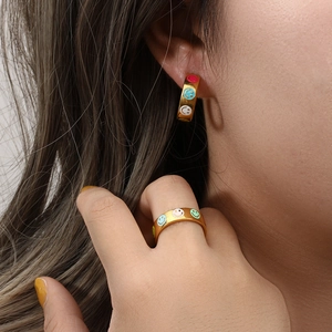 Close-up of gold 18K plated hoop earrings and ring with colorful enamel smiley faces
