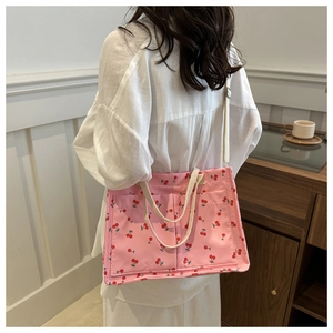 Detail view of the pink cherry print tote bag shown on a model for size perspective