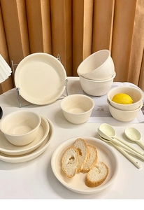 Macro shot of creamy yellow ceramic dinnerware set including bowls, plates and spoons