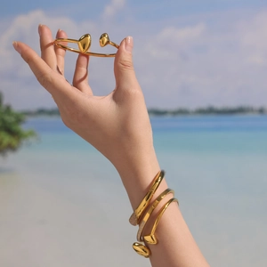 Bracelets clou en acier inoxydable doré 18 carats sur un fond de vacances à la plage