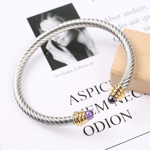 Silver cable wire bracelet with gold accents and purple gemstones on fashion background