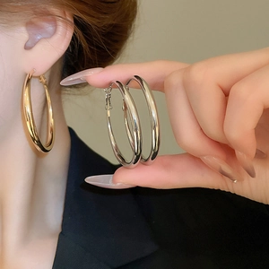 Close-up of model wearing large high-polished gold and silver hoop earrings in minimalist style