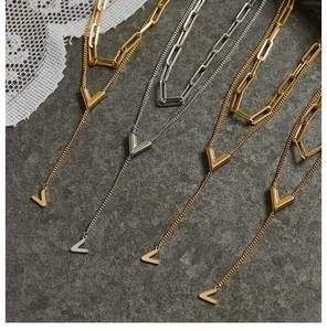 Detailed view of layered V-shaped pendant necklaces in gold and silver finishes