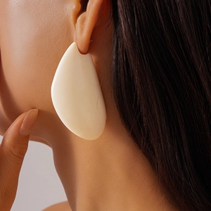 Gros plan d'une boucle d'oreille géométrique en résine crème sur une femme mannequin