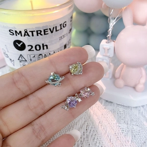 Macro shot of cubic zirconia star and moon earrings in blue, yellow, and pink colors