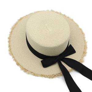 Detailed macro view of woven raffia texture and chic black ribbon bow on a flat top straw hat