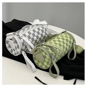 Detail view of quilted cylinder crossbody bags in green and white with wide straps