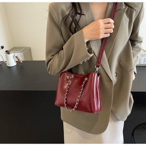 Detail der weinroten Lackleder-Eimertasche mit Silberkette und Schultergurt am Modell