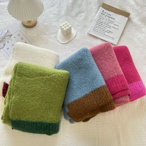 Detail of folded knitted cashmere-feel scarves in green, pink, and white tones