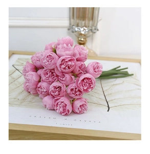 Close-up of pink artificial peony bouquet resting on books with a soft natural lighting
