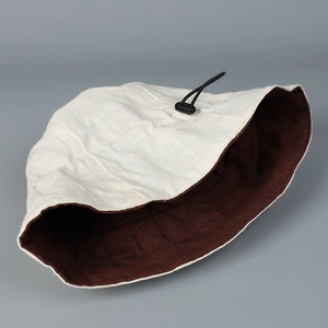 Detail of linen sun hat showing the two-tone design and adjustable black drawstring buckle