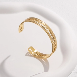 Detail of gold open cuff bracelet with hollow geometric patterns and beaded edges