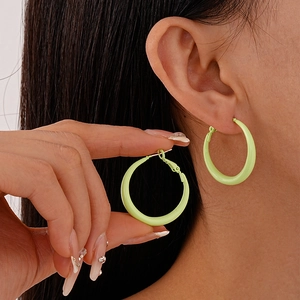 Close-up of light green candy color hoop earrings worn by a model for a minimalist look