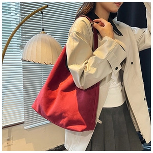 Red faux suede tote bag shown on a model wearing a beige trench coat for a stylish look