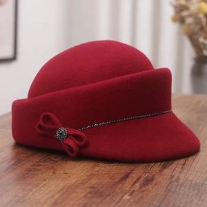 Detailed view of a wool felt equestrian hat with a rhinestone bow on a wooden surface