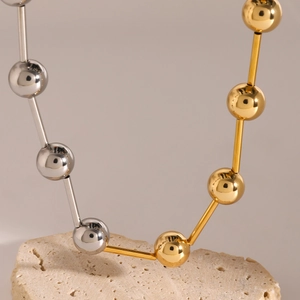 Two-tone 18k gold and silver stainless steel ball necklace on a natural stone base