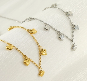 Detail of gold and silver heart-shaped pendant bracelets on white silk fabric