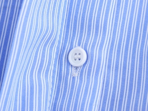 Detailed close-up of blue striped shirt fabric with a white button and fine woven texture
