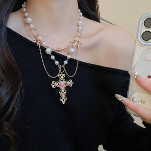 Detail view of a multi-layer pearl necklace with a rhinestone-set baroque cross pendant