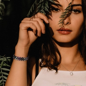 Doppellagiges Armband aus Amethyst und Hämatit, getragen von einem Modell in der Sonne