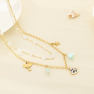 Detail of gold double-layered necklace with star, elephant and blue bead charms