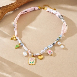 Detail of silk-wrapped chain necklace with floral print and gold-plated charms