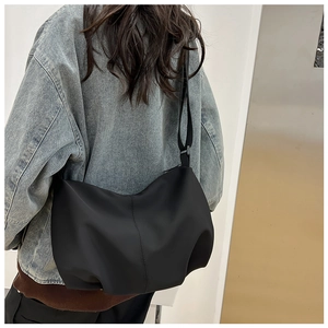 Minimalist black dumpling crossbody bag shown on model for silhouette and drape effect