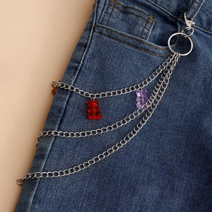 Detail of layered silver metal pant chain with red and purple gummy bear pendants on jeans