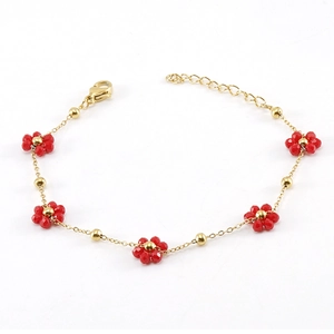 Elegant gold chain bracelet with red crystal flowers on a clean white background