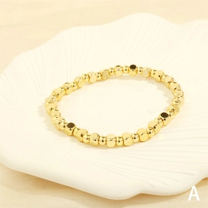 Detail of gold square beaded elastic bracelet on a white shell ceramic tray