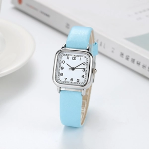 Detail of a square quartz watch with a light blue leather strap and a white numeric dial