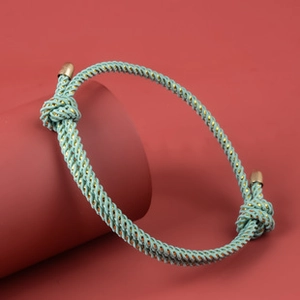 Close-up of turquoise braided bracelet with gold metal clasp on a red stand