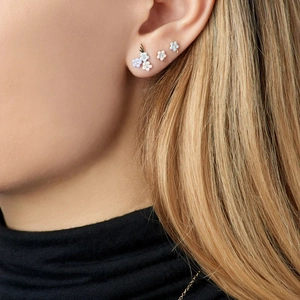 Detail of floral enamel stud earrings set with crystal centers worn on the ear