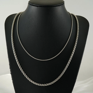 Set of two silver stainless steel chains with thick and thin link designs on a black bust