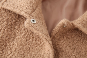 Macro shot of camel teddy fleece texture and silver snap button on a winter coat