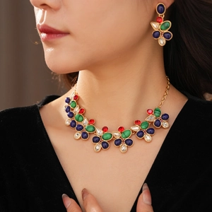 Nahaufnahme von Vintage-Schmuckset mit bunten Edelsteinen auf goldener Kette und Ohrringen