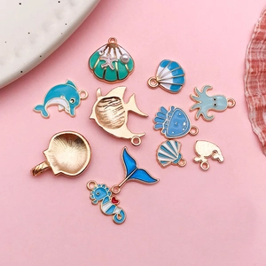 DIY colorful enamel ocean animal charms including dolphins and shells on pink background