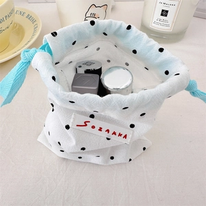 Close-up of a polka dot drawstring bag filled with cosmetics in a cozy setting