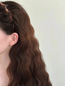 Gros plan d'un serre-tête ondulé en écaille de tortue sur des cheveux longs bouclés