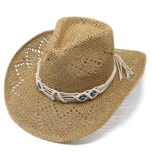 Handmade hollow straw cowboy hat with bohemian evil eye bead band on white background