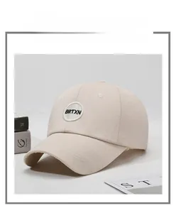 Detailed close-up of light beige baseball cap with BRTXN circular embroidery patch