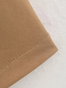 Gros plan détaillé du tissu en maille kaki avec coutures précises et texture sergée