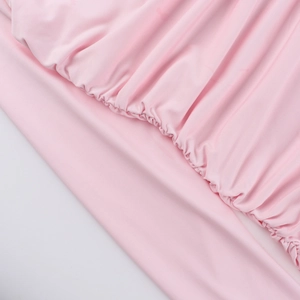 Detailed close-up of pink elastic fabric ruffles and precision stitching on dress