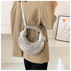 Detail of silver metallic woven handbag featuring unique knotted design and noodle straps