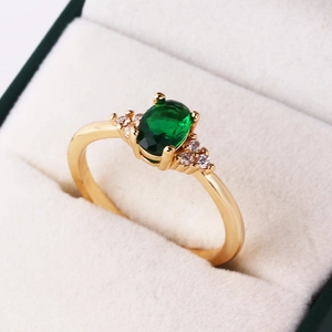 Macro shot of an oval emerald zircon ring with gold plating in a velvet jewelry box